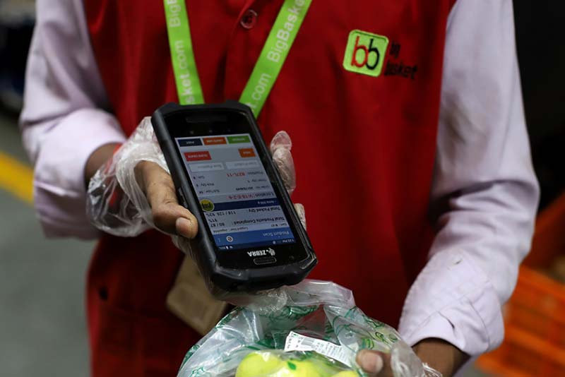 A worker scans a product while fulfilling an order at a BigBasket warehouse in New Delhi, India.