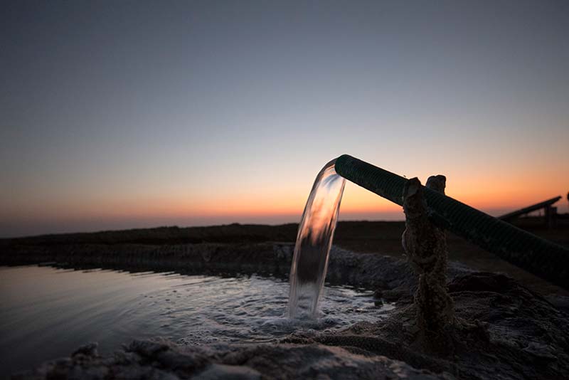 Energy from solar panels, pump up salty groundwater into salt pans as the sun sets in Little Rann Off Kutch, India.