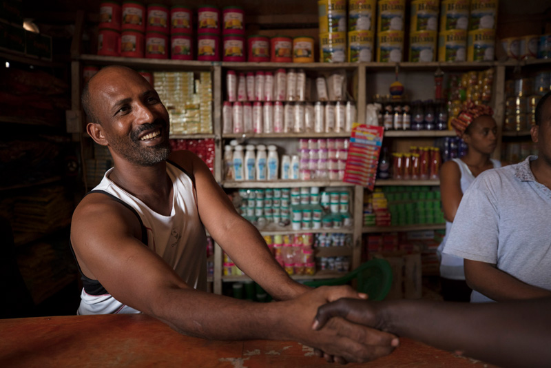 Mesfin Gitahon, refugee and owner of a food shop, greets and talks to customers in Kakuma.