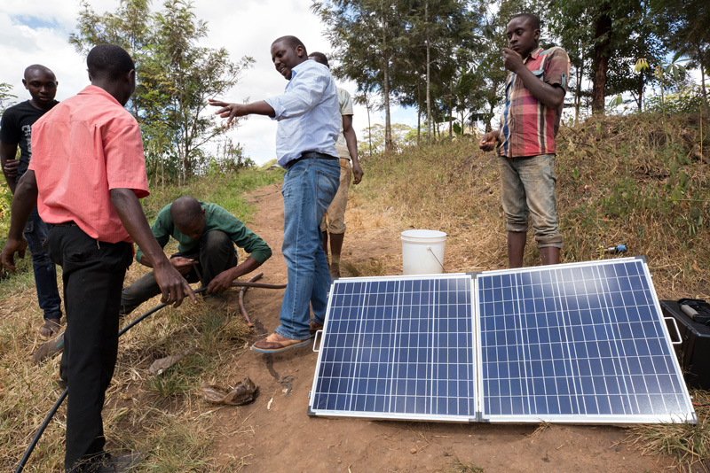Charles Ngatia Kaombe, an agriculture engineer at SunCulture, (center) gives a demonstration of the SunCulture Rain Maker--a solar-panel irrigation system at a farm in Makuyu, Kenya